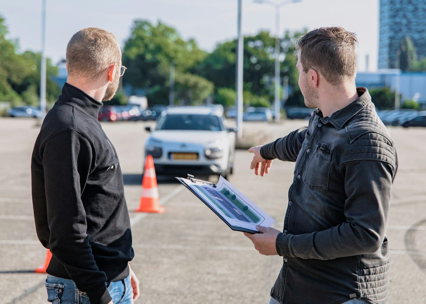 Rij-instructeur met klembord bespreekt het rijexamen naast de lesauto